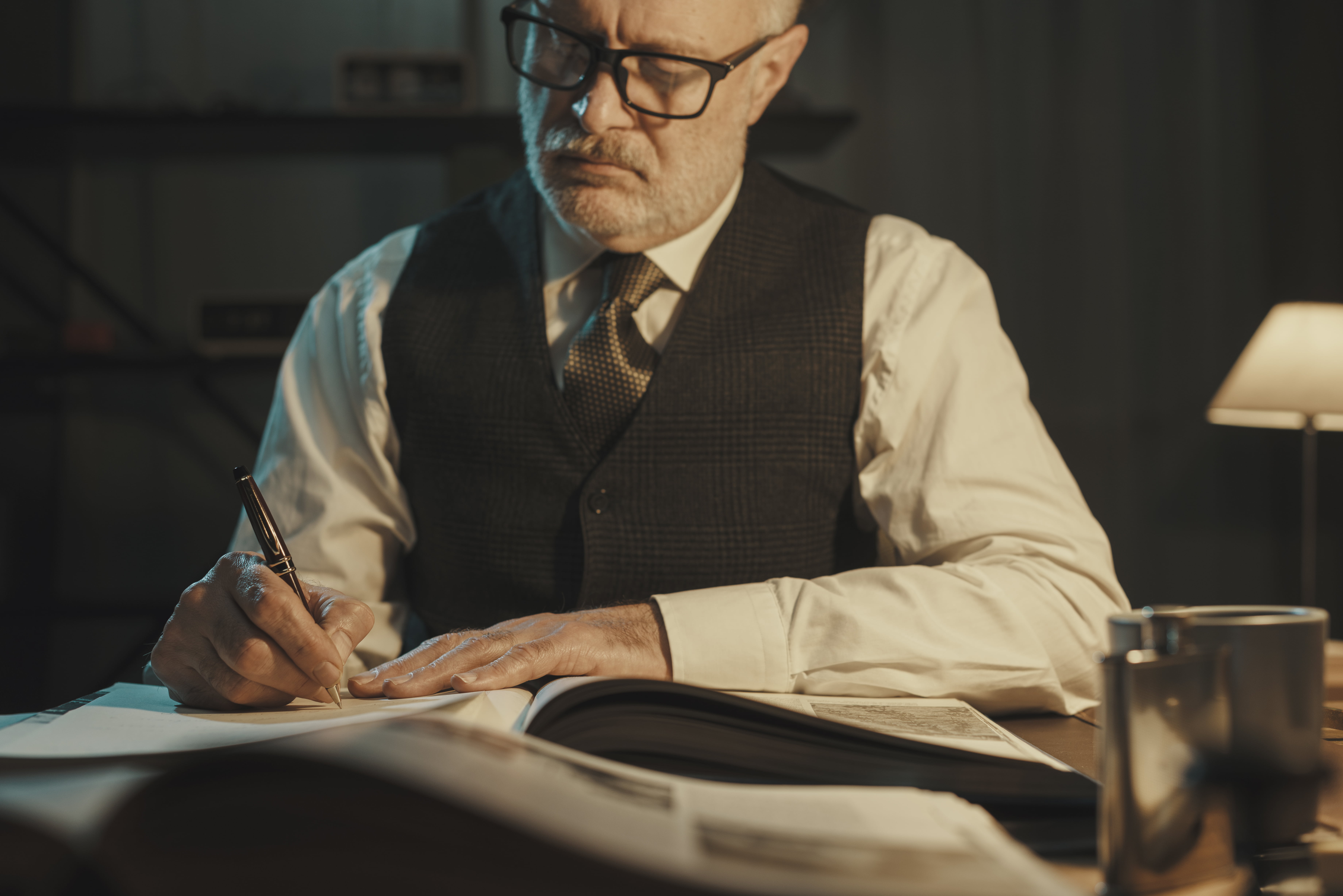 Academic professor writing down notes and reading a book