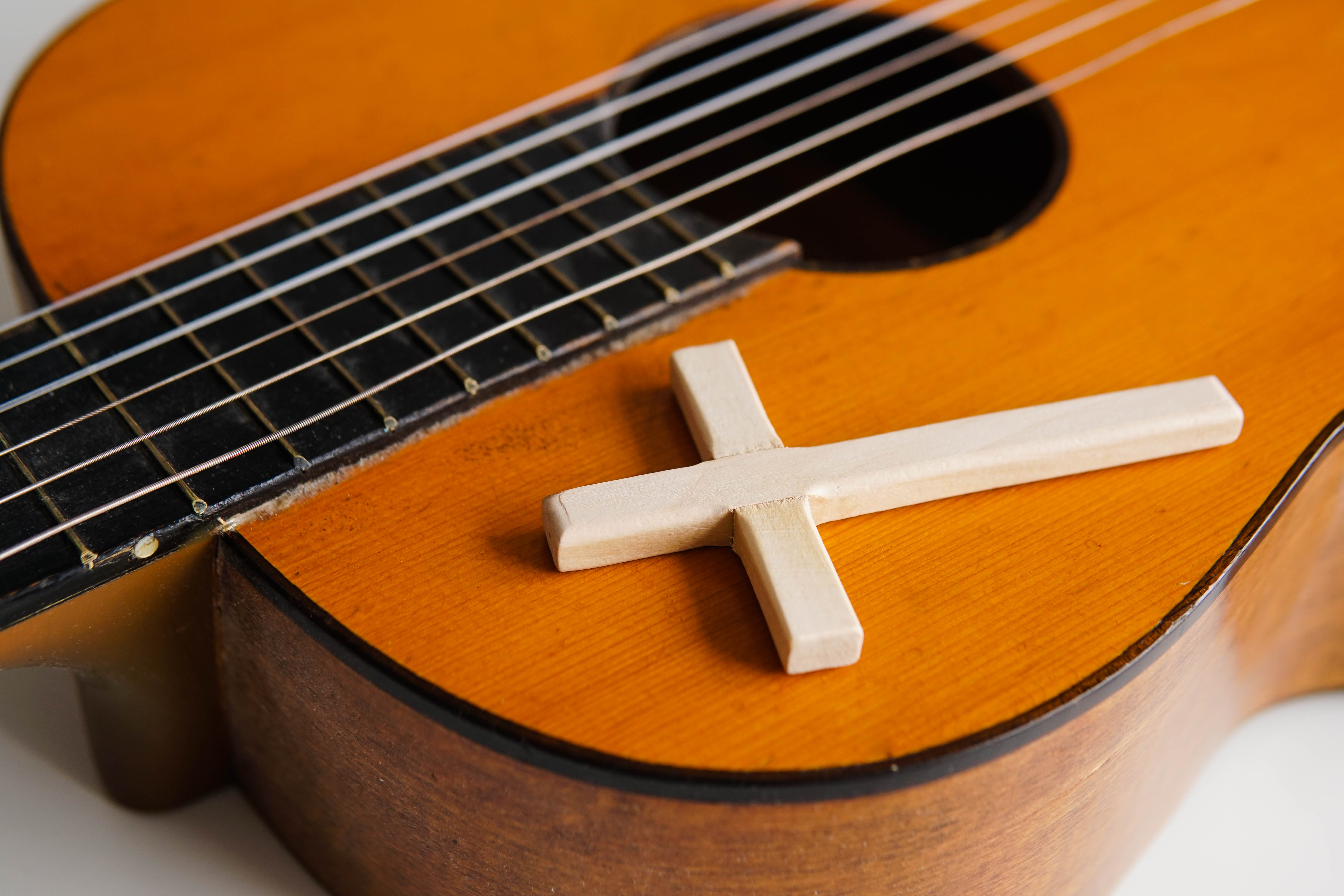 Acoustic guitar with wooden cross on the table close up. Christian music.