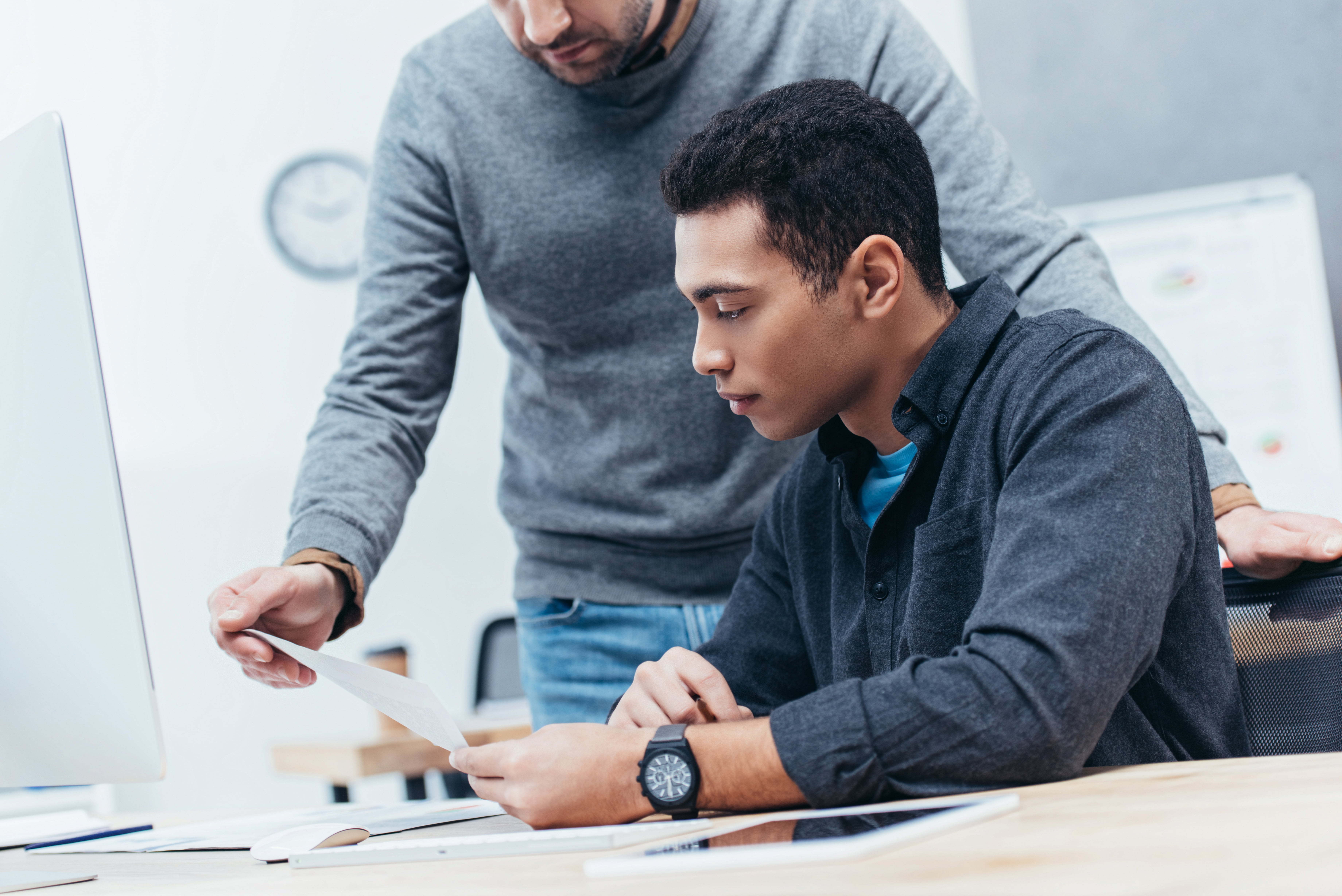 cropped shot of two businessmen looking at document at workplace