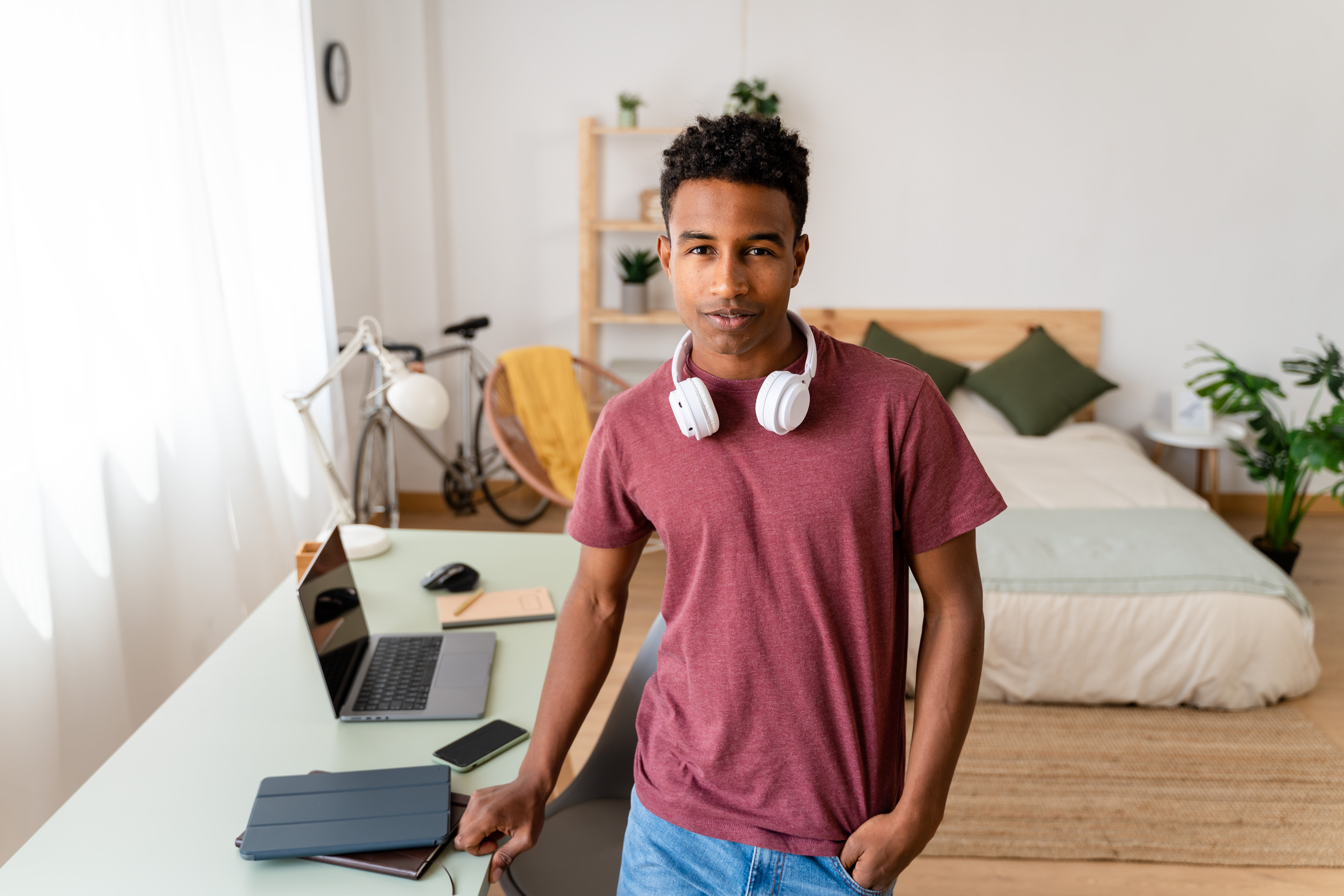 Young man with freelance job standing by desk.