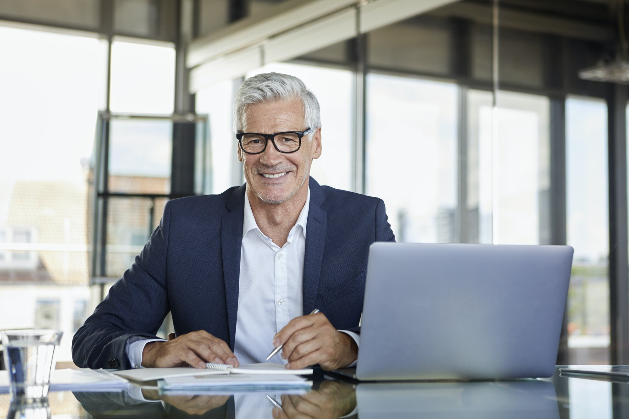 Businessman working at laptop, taking notes in notebook