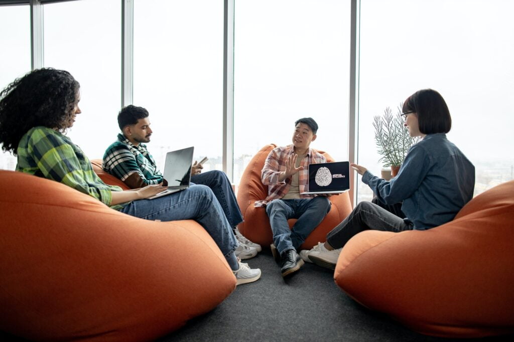 Male with AI project on laptop chatting with teammates