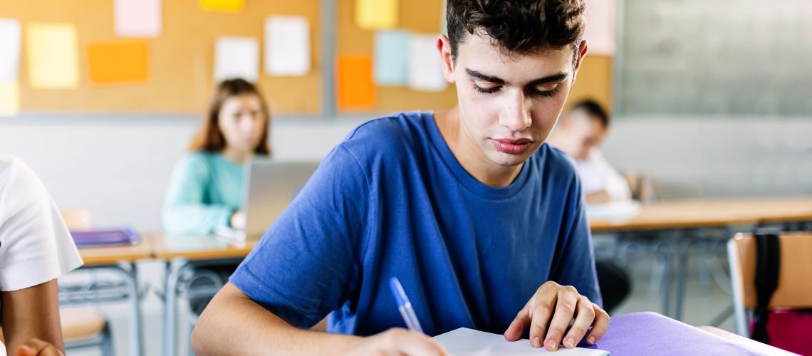 High school young student writing to notebook in class lecture