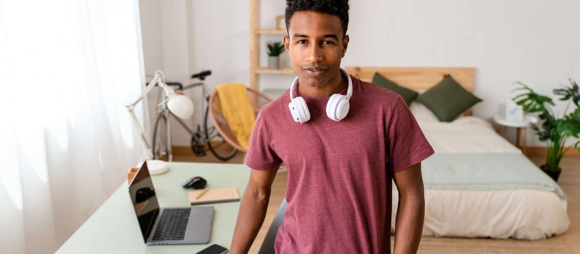 Young man with freelance job standing by desk.